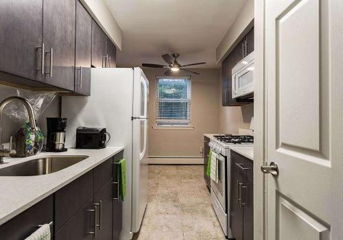 Kitchen with white appliances 和 dark brown cabinets at 沃灵顿口岸 apartments for rent.